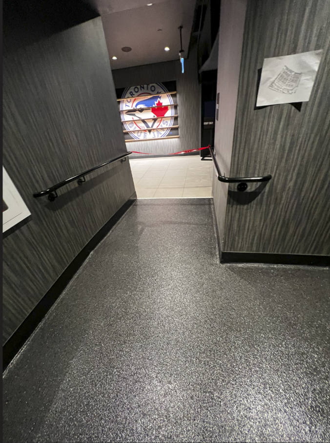 View down a hallway with handrails leading to a room with a colorful wall mural.