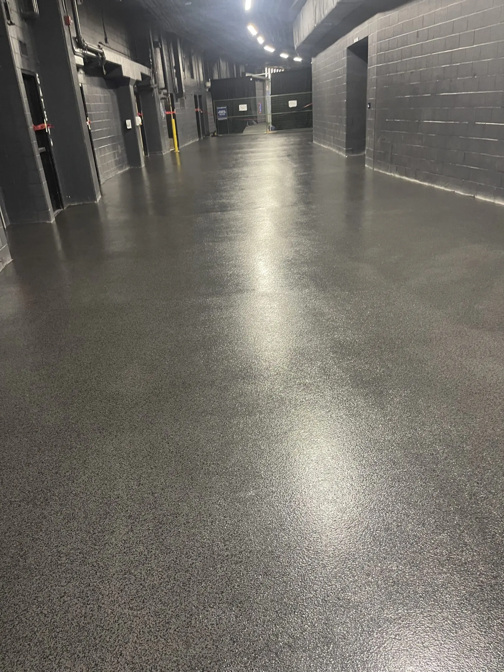 Empty hallway with polished concrete floor and overhead lights.