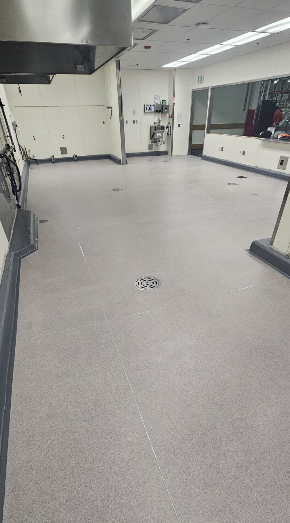 Clean, empty laboratory or workspace with smooth flooring and drain.