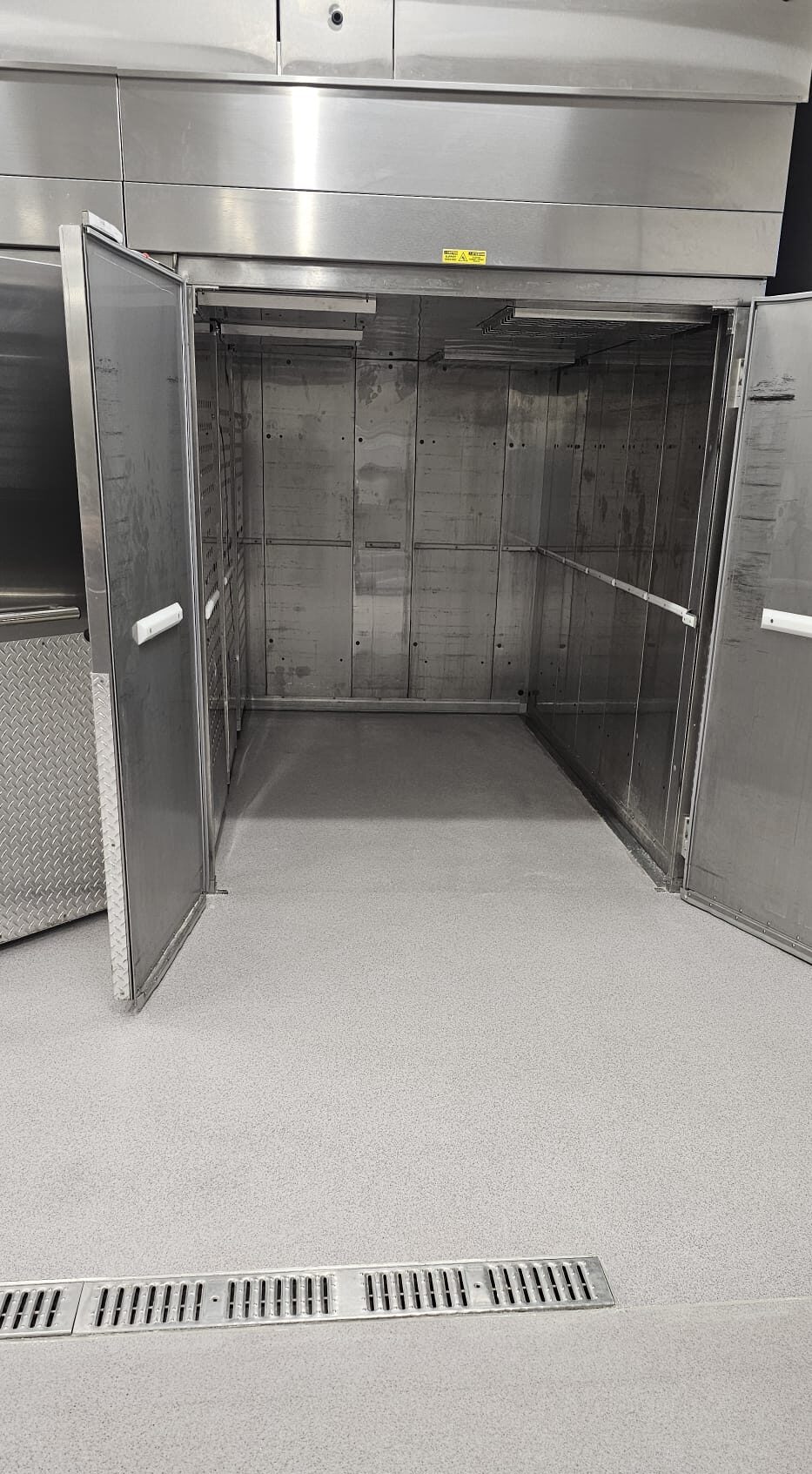 Open doors reveal an empty industrial walk-in freezer or storage room.